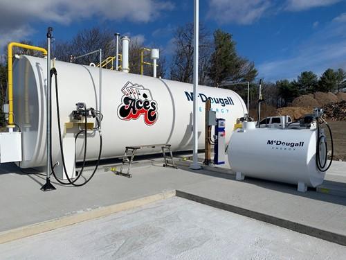Shows outdoor shot of large white tank with Mcdougall Energy logo on it and Aces logo
