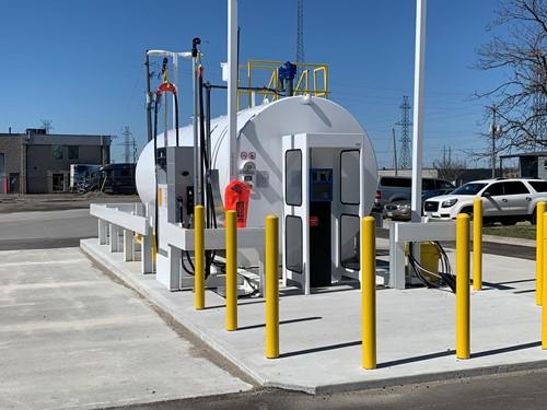 Show outside shot of large stationary fuel tank and yellow guard posts surrounding it