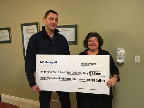 Shows 2 people holding a large cheque from McDougall Energy